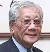Kuniwo Nakamura, älterer weißhaariger Herr im Anzug.
