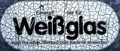 Verwitternder Hinweis an einem Glas-Recycling-Container