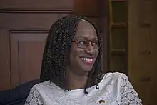 Andrea Bowman. Porträt einer jugendlichen, dunkelhäutigen Frau mit Brille und aufwändiger afrikanischer Zöpfchen-Frisur.