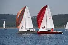 Das Bild zeigt zwei 16m²-Jollenkreuzer mit gesetzten Spinnaker in einer Wettfahrt auf dem Großen Brombachsee