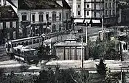 Abfahrtsstelle der Vöslauer Linie am Josefsplatz, links ein aus Wien angekommener Zug der Badner Bahn, davor wartend ein grün-créme lackierter Wagen der Serie 92–99.