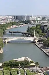 Farbige Obersicht auf einen Fluss mit einer begrünten Insel im Vordergrund und mehreren Brücken. Im Hintergrund moderne Häuser und Bäume.