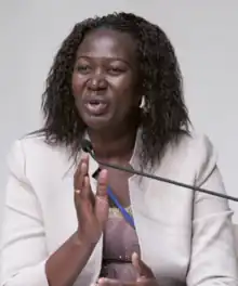 Awut Deng Acuil. Eine Frau mittleren Alters in einem weißen Kostüm.