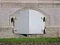 Stahltür als Splitterschutz vor einem Luftschutz-Kellerfenster