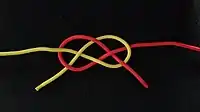 Trossenknoten (#1428)Der Trossenknoten kann für einen dekorativen Zweck flach gebunden werden. Hier liegen die beiden Enden auf derselben Seite des Knotens. Dies ist weniger fest und sicher, als wenn der Knoten die Enden diagonal gegenüber hat.