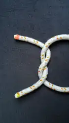 Das Bild 4 von oben um 90° im UZS gedreht.Ein „Z“ geschlagener Halber Knoten (das Seil mit rotem Ende zeigt den Buchstaben Z).