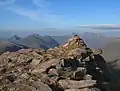 Der Gipfelcairn des Beinn Tarsuinn, im Hintergrund links Beinn Dearg Beag und Beinn Dearg Mòr, rechts das Massiv des An Teallach