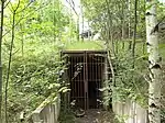 Nahe dem ehemaligen Westportal liegt ein Wartungszugang; im Hintergrund ist die Brücke der neutrassierten Strecke über die B&nbsp;27 zu sehen
