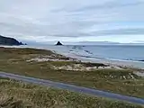 Foto eines Strandes, im Hintergrund eine Insel im Meer