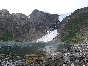 Oben der Isfjordjøkelen, ein Teilgletscher des Øksfjordjøkelen, unten der Gletscher Nerisen, ein sogenannter „regenerierter Gletscher“, der von den Lawinen des Isfjordjøkelen gespeist wird. Das Eis der Gletscher wurde bis 1949 von den Fischern und Händlern zu Kühlung des Fangs genutzt.