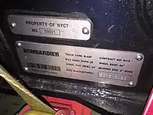 Zwei bedruckte und gestanzte Blechschlder mit Informationen zum Drehgestell. Schild 1: PROPERTY OF NYCT NO. 55021. Schild 2: BOMBARDIER TRUCK TYPE: B-45P CONTRACT NO: R179 / MAX LOAD: 45500 LB WHEEL BASE: 82" / WHEEL SIZE (NEW): 34" BEARING SIZE: 5" BORE / DATE MANUFACTURED: 2016.3.28