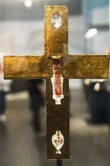 Rückseite des Goldkreuzes, umlaufender Schriftzug und andere Ornamenten drei Stellen, an denen die Bergkristalle eingelassen sind, scheint von der Vorderseite das Licht durch