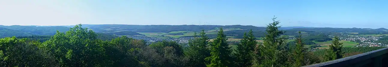 Die Hochflächen vom Koppeturm im Ostteil der Zollbuche aus etwa 470&nbsp;m Höhe gesehen; links der Mitte die Angelburg (609&nbsp;m; Sendemast), rechts der Mitte Daubhaus (552&nbsp;m) und Allberg (528&nbsp;m) am Ostrand, dazwischen ist das Relief auffällig unbewegt. Ganz rechts im Bild der Rimberg (497&nbsp;m; Damshäuser Kuppen), links davon in hinterer Reihe das Arennest (592&nbsp;m; Sackpfeifen-Vorhöhen) und die Sackpfeife (674&nbsp;m); der Schwarzenberg (561&nbsp;m; Breidenbacher Grund) wird bereits teilweise durch den Allberg verdeckt. Im zentralen Vordergrund Weidenhausen, im rechten Gladenbach.Für Details siehe Bildbeschreibungsseite!
