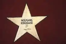 fünfzackiger, goldener Stern, eingelassen auf rotem Untergrund mit der Inschrift Wolfgang Kohlhaase, Autor, Writer, 1931 und Unterschrift