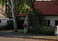 Wegekreuz vor einfachem Wohnhaus