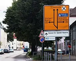 Vorwegweiser, an der Straße vor der Kreuzung. Die Ausführung des Pfeils im Wegweiser ist jedoch nach den RWB nicht zulässig.