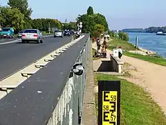 Rheinpegel an der Bundesstraße&nbsp;42. Die Anzeige am Pegelstab reicht bis 6&nbsp;Meter, bei 5,46&nbsp;Meter wird hier die Fahrbahn überspült. 1988 wurde hier ein Pegel von 5,80&nbsp;Meter erreicht.