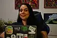 Eine lächelnde Frau auf einem Stuhl hinter einem Laptop.