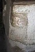 Taufbecken, Kopf an einer Ecke