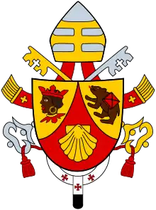 Das Wappenschild ist dreigeteilt. Oben links ist eine dunkelhäutige Figur auf gelbem Untergrund, oben rechts ein Bär auf gelbem Untergrund und unten eine gelbe Jakobsmuschel auf rotem Untergrund. Auf dem Wappen sind die Papstkrone und zwei Schlüssel und um das Wappen sind weitere Ornamente verteilt.