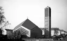 Schwarz-Weiß-Bild des noch nicht von Bäumen eingewachsenen Baukörpers, rechts der Glockenturm