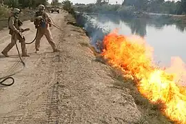 Mit einem Flammenwerfer werden potentielle Verstecke von IEDs abgebrannt