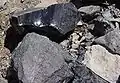 Obsidian (glänzend), Rhyolith (mattgrau im Vordergrund) und Bims (heller, rechts)