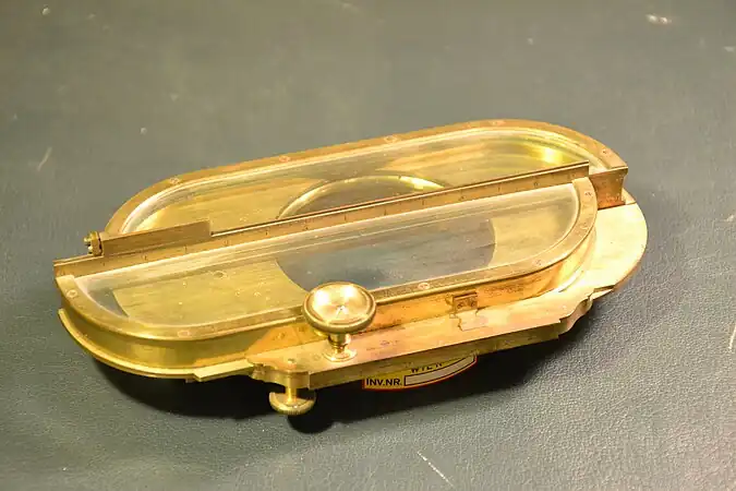 Heliometerlinse von Dollond, um 1790 (Universitätssternwarte Wien), zum Vorsatz vor einen Refraktor mit 6,7 cm Öffnung. Die Linsenhälften werden mit der Schraube gegeneinander verschoben, Ablesung der Verschiebung auf der Skala (mit Nonius) in der Mitte.