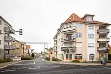 Links und rechts einer kleinen Straße mit dem Schild Tempolimit 30 sind Häuser mit Balkonen in gutem Erhaltungszustand zu sehen.