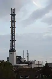 Stadtwerketurm mit den Unterbauten des HKW II sowie den Ersatzschornstein für HKW I und Heizwerk im Hintergrund (links, 2014); Nachtaufnahme mit der charakteristisch grünen Beleuchtung (2012)