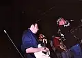 Drei Bandmitglieder von Earth Crisis mit einem schwarzen X auf der Hand, Baggy Pants und Kapuzenpullovern bei einem Konzert 1996 in Indianapolis