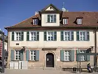 Rückwärtige Häuserzeile: Gemeindezentrum am Bahnhofplatz 2 (links) und Pfarrhaus am Bahnhofplatz 3 (rechts)