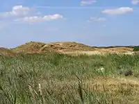 An Loch 14 werden zwei blinde Schläge gefordert. Zunächst muss die Düne mit einem präzisen Schlag überwunden und das dahinterliegende Wasserhindernis links und das Rough rechts vermieden werden.