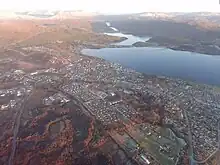 Luftbild auf eine an einem Gewässer gelegene Stadt hinab