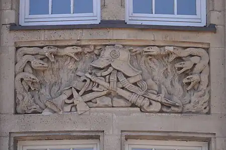 Relief im 1. ObergeschossSchlangen symbolisieren die Feuersbrunst