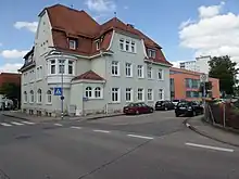 Zu sehen ist eine Kreuzung und das vom Finanzamt Ehingen genutzte Gebäude auf der anderen Straßenseite. In der Bildmitte ist der Altbau und rechts der angebaute Neubau.