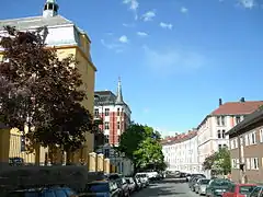 Foto einer Straße, gesäumt von Autos und etwa vierstöckigen Gebäuden