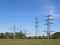 Eine Bahnstromleitung unterquert zwei Drehstromleitungen auf sehr niedrigen Masten