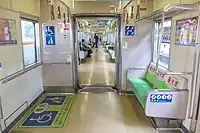 Innenraum eines durchgängigen Zuges der Baureihe&nbsp;2000 der U-Bahn&nbsp;Fukuoka mit Mehrzweckfläche für Rollstühle und Kinderwagen und priority seats