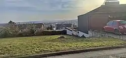 Fundplatz Gönnersdorf im Jahr 2021. Blick vom Mühlenweg nach Süden zur Eduard-Mörike-Straße und zum Rheintal mit der Eifel im Hintergrund. Auf dem Wiesengrundstück neben der schwarz gestrichenen Garage befand sich die Fundkonzentration IV, weiter unten neben der weißen Garage die Fundkonzentration III.