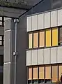 Fassadendetails: Waschbetonbrüstungen, Leichtmetallfenster mit farbigen Jalousien, Treppenturm mit Waschbetonrippen (2019)