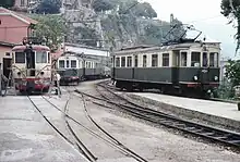 Triebwagen (rechts) und Beiwagen (Mitte) der Fleimstalbahn in Genua, 1980