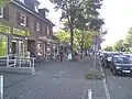 Häuserzeile an der Sülldorfer Landstraße, links hinten das ehem. Kino Lichtburg Iserbrook, dann ein Supermarkt (2023 abgerissen)
