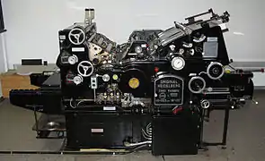 Rechts oben sieht man den Anlagestapel mit dem Sauggreifer, der den Bogen in Einzelanlage über den gewölbten Anlegetisch in die Maschine führt.
