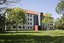 Ein vierstöckiges Gebäude mit spitzem Dach und eine außen montierten Lift.