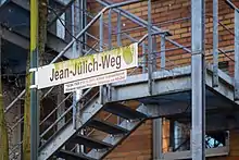 Bemoostes Straßenschild mit Kurzbiografie