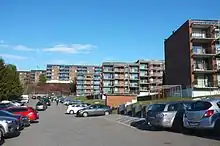 Foto von vielen baugleichen Wohnblöcken. Im Vordergrund parken viele Autos.