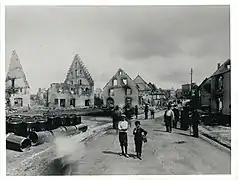 Die Käferstraße, etwa von der Kreuzung mit der Wöhrdenstraße bzw. Wasserstraße aus. Links das Anwesen Marie Engeßer, der Brandherd. Daneben, Bildmitte, die Ruine der Restauration Kuttruff. Ganz hinten rechts das Amtsgefängnis mit dem markanten Turm.