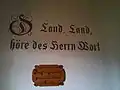 biblisches Wort an der Wand hinter der Kanzel