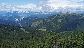 Blick vom Wetterkogel auf der Hochalpe nach Westnordwest über den Klein-Gößgraben. Links mittig das Mitteregg, an dem der Groß-Gößgraben abzweigt. Am Ausgang des Grabens die Leobener Stadtteile Göss und Leitendorf mit dem weithin sichtbaren Kalkwerk Leoben.